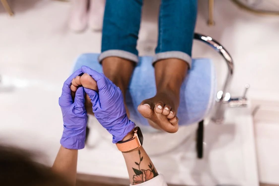 A woman in jeans getting a foot bath and massage from a person wearing gloves